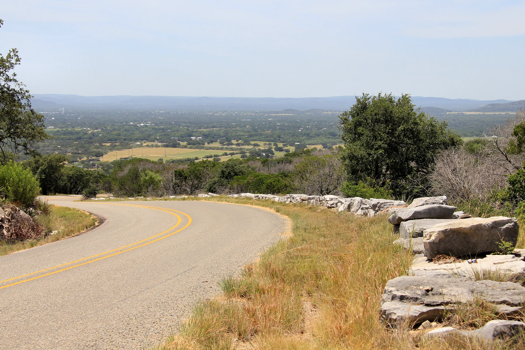 Guard walls along Park Road 4 as it descends into Hoover's Valley toward Inks Lake State Park . The Civilian Conservation Corps built the road between 1934 and 1942.