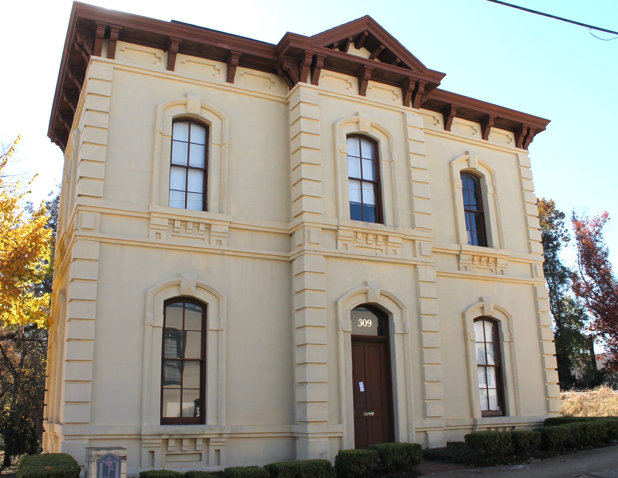 Smith County Jail in Tyler, Texas. State historical marker inscription - Houston architect Eugene T. Heiner and builder Henry Kane designed and built this structure in 1880-81 to serve as Smith County's fourth jail. An 1894 second-story addition doubled the jail's cell space. The building was replaced by a new jail in 1916 and subsequently housed the Lewis Hotel until 1986. It features classical detailing of the Italianate style, a stucco finish scored to look like cut stone, elaborate window molds and consoles, and classical beltcourses. Recorded Texas Historic Landmark - 1993