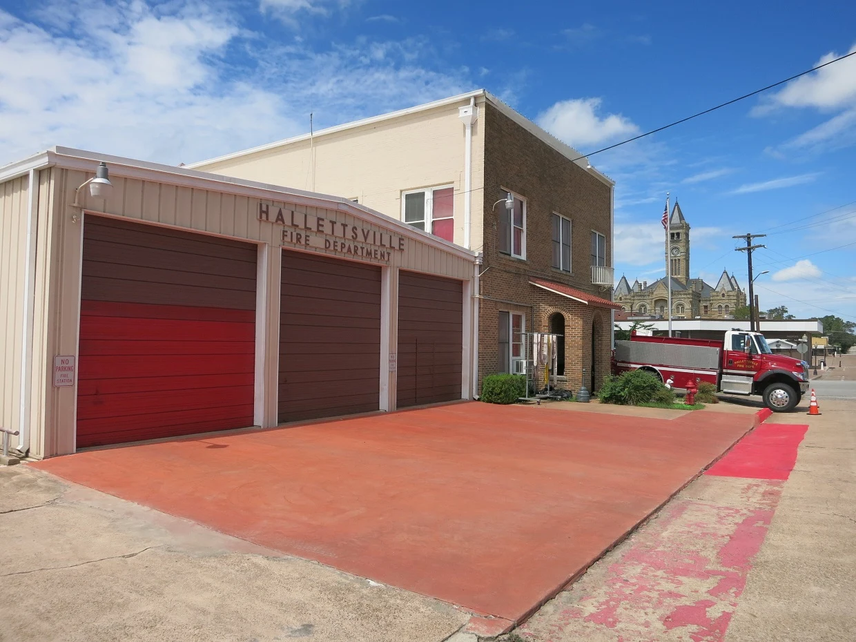 Photo shows the Fire Department at 204 E 4th Street, Hallettsville, TX 77964. View is toward the northwest with the Lavaca County Courthouse in the background.